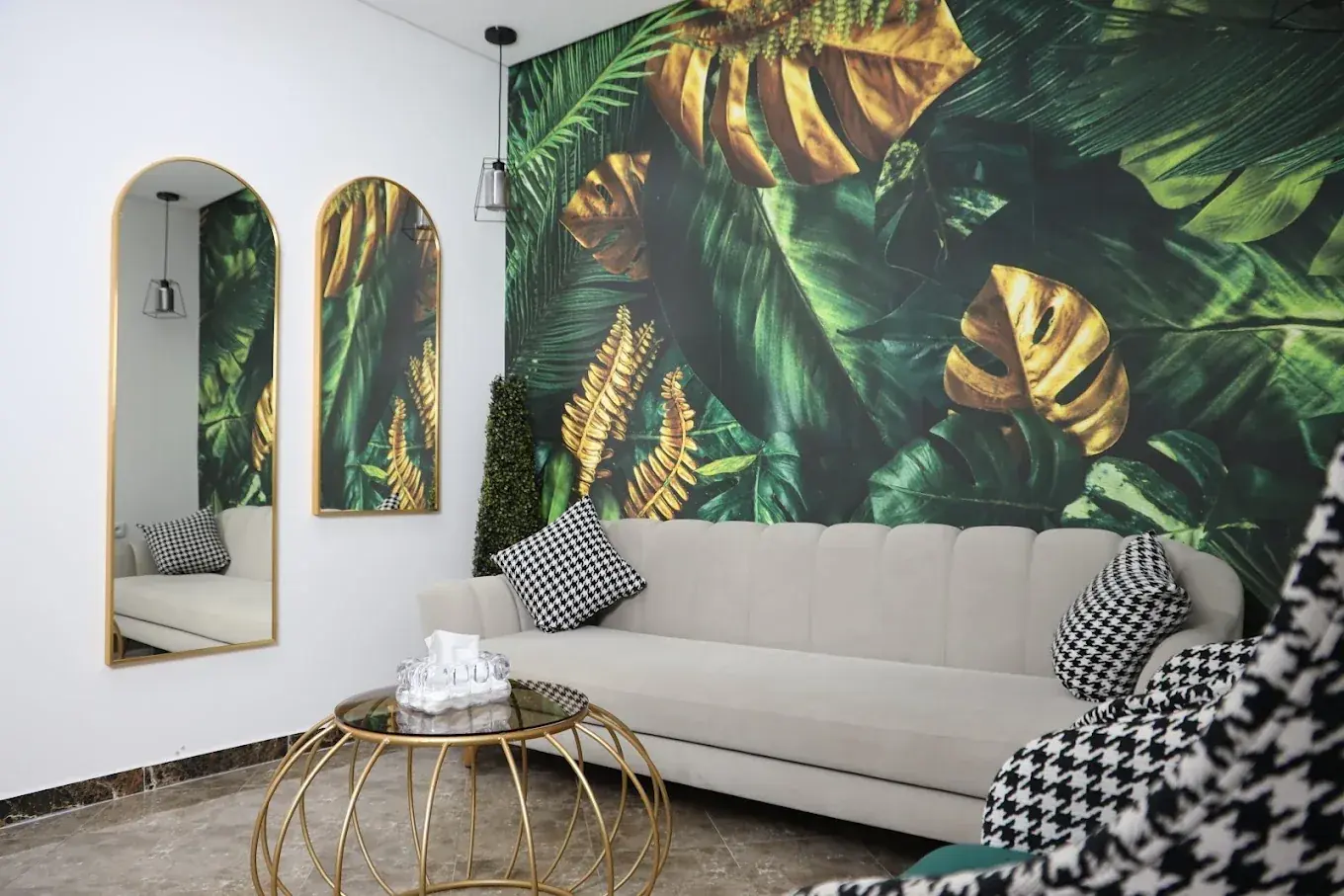 Le salon d'attente de MK Laser, canapé clair, miroirs dorés et mur de feuilles vertes et dorées